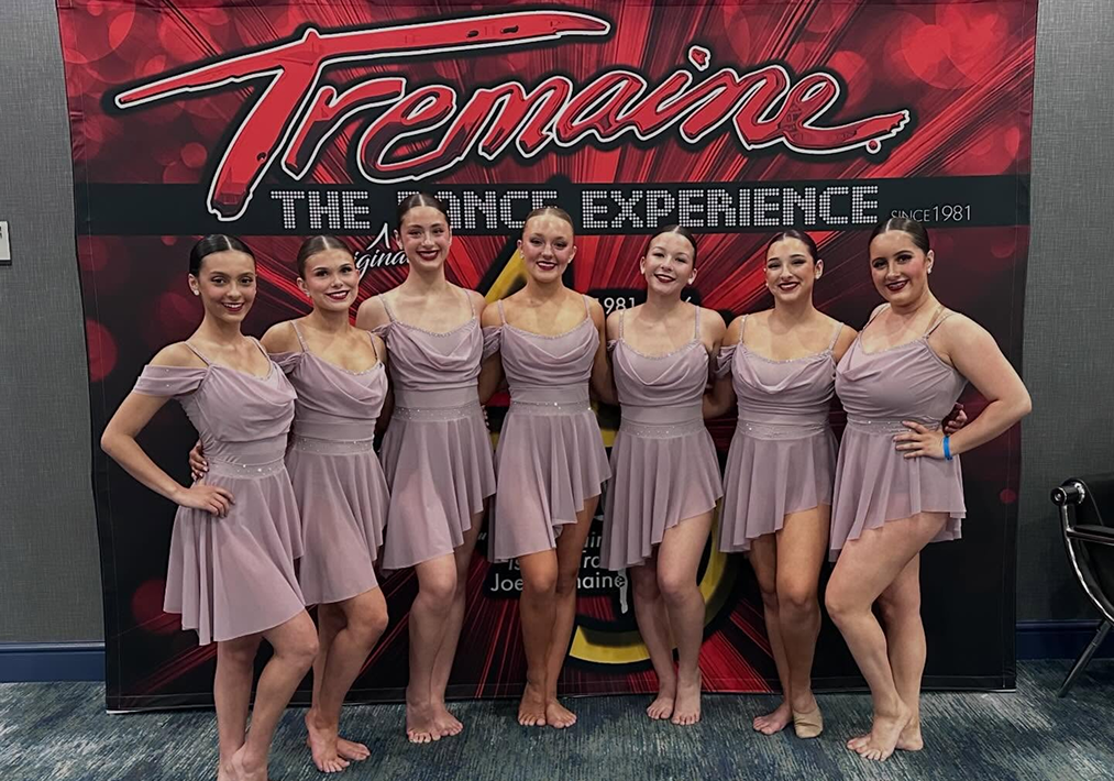 Eight dancers in matching lavender costumes pose together at Tremaine Dance Experience.