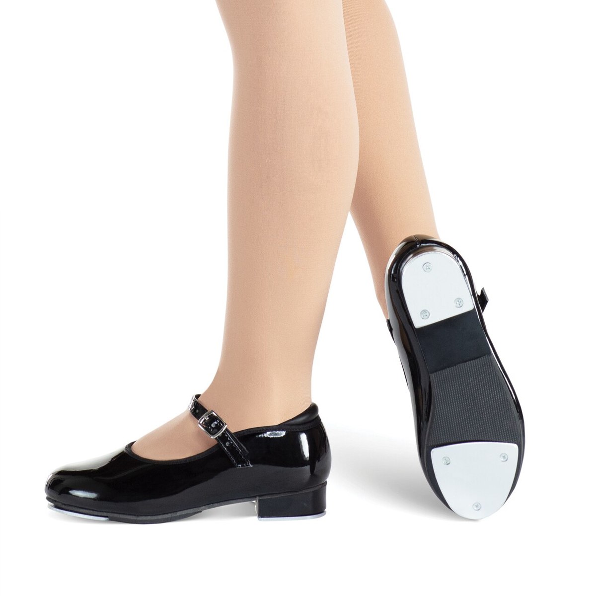 Child wearing black tap dance shoes with one shoe showing the sole.