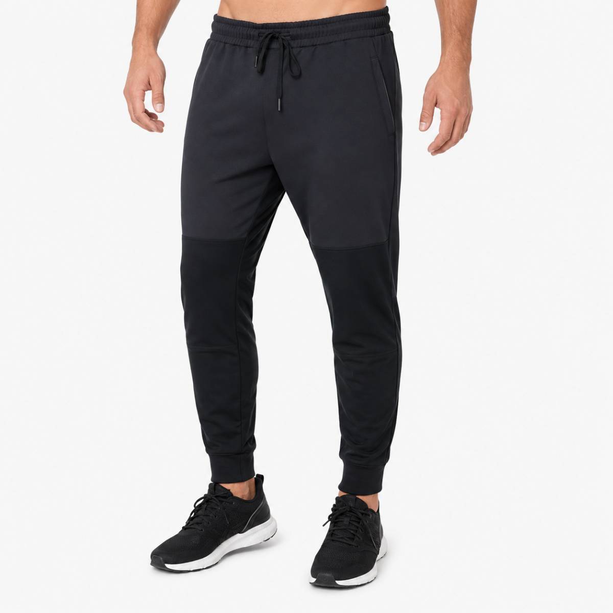 Man wearing black athletic jogger pants and black sneakers.