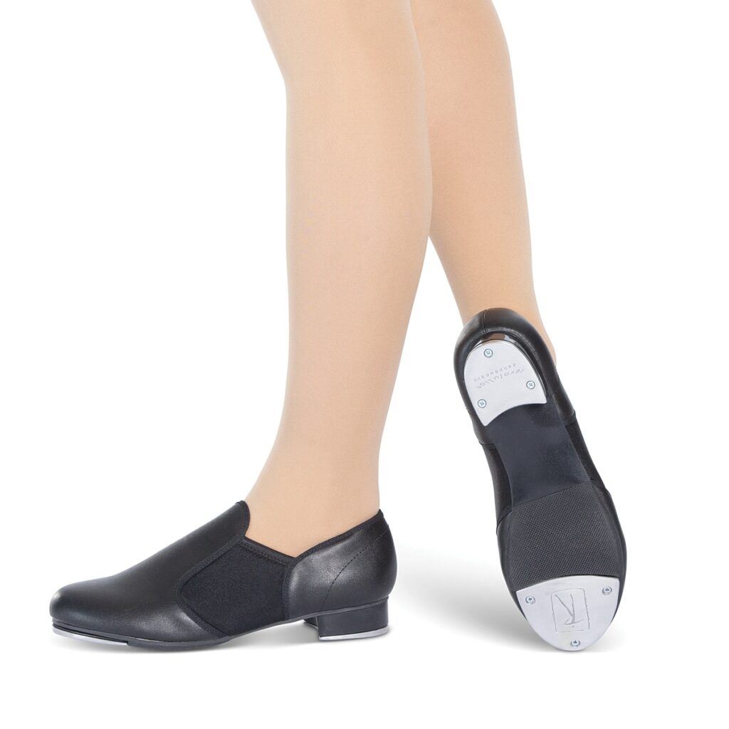 Person wearing black jazz shoes on feet, shown from calf down.