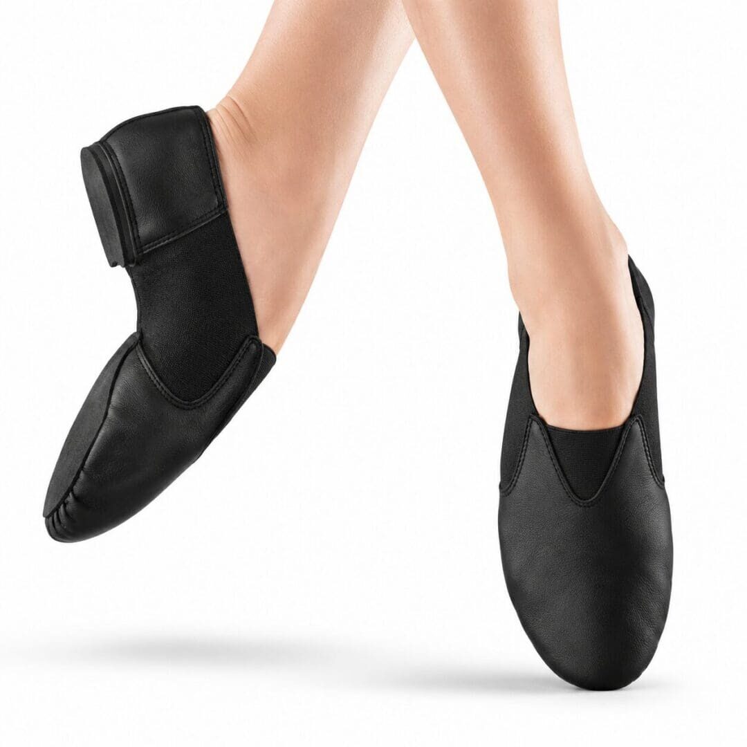 Black jazz dance shoes worn by a dancer with crossed feet.